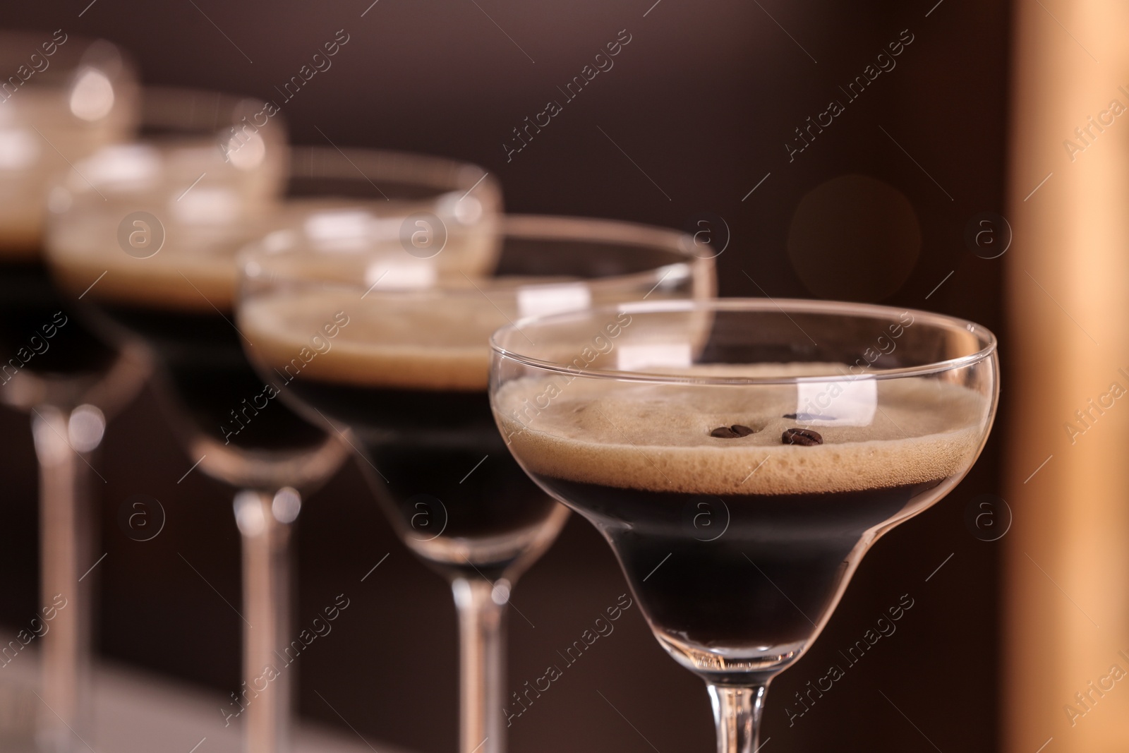 Photo of Glasses of delicious Espresso Martini on blurred background. Alcohol cocktail