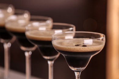 Photo of Glasses of delicious Espresso Martini on blurred background. Alcohol cocktail