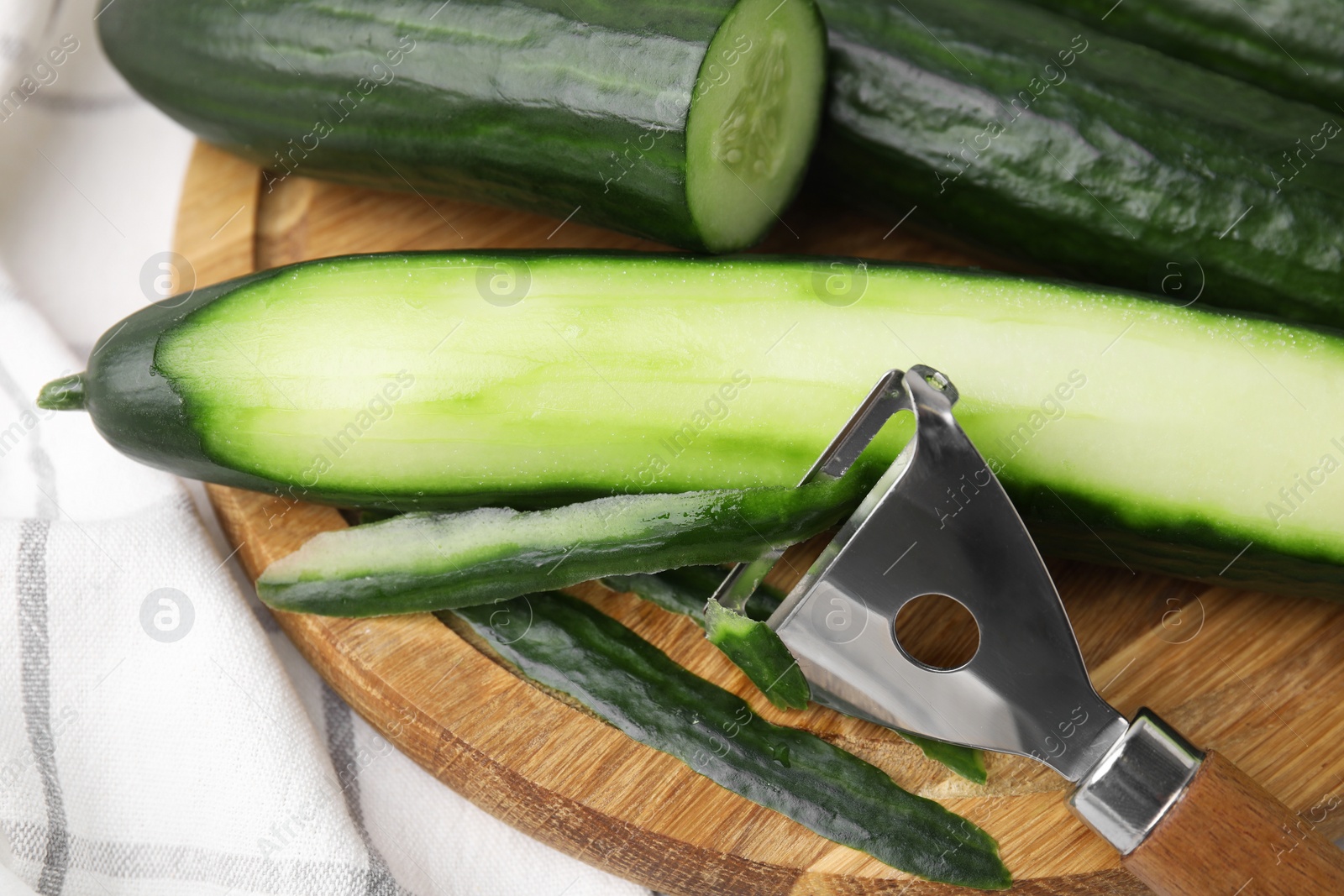 Photo of Fresh cucumbers and peeler on table, closeup