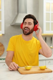 Photo of Happy man listening music with headphones in kitchen