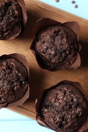 Photo of Tasty chocolate muffins on light blue wooden table, top view