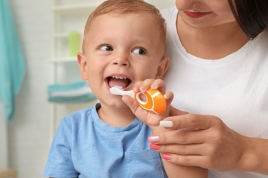 Woman and her son with toothbrush on blurred background