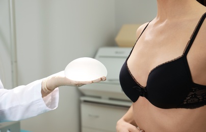 Doctor showing silicone implant for breast augmentation to patient in clinic, closeup. Cosmetic surgery