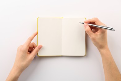 Photo of Woman writing in notebook on white background, top view