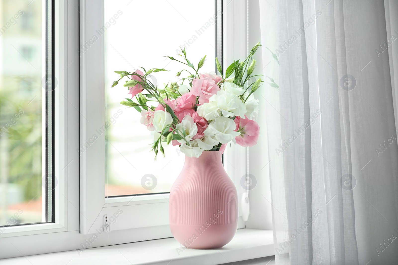 Photo of Vase with beautiful flowers on window sill