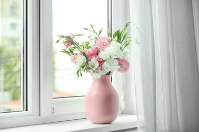 Photo of Vase with beautiful flowers on window sill