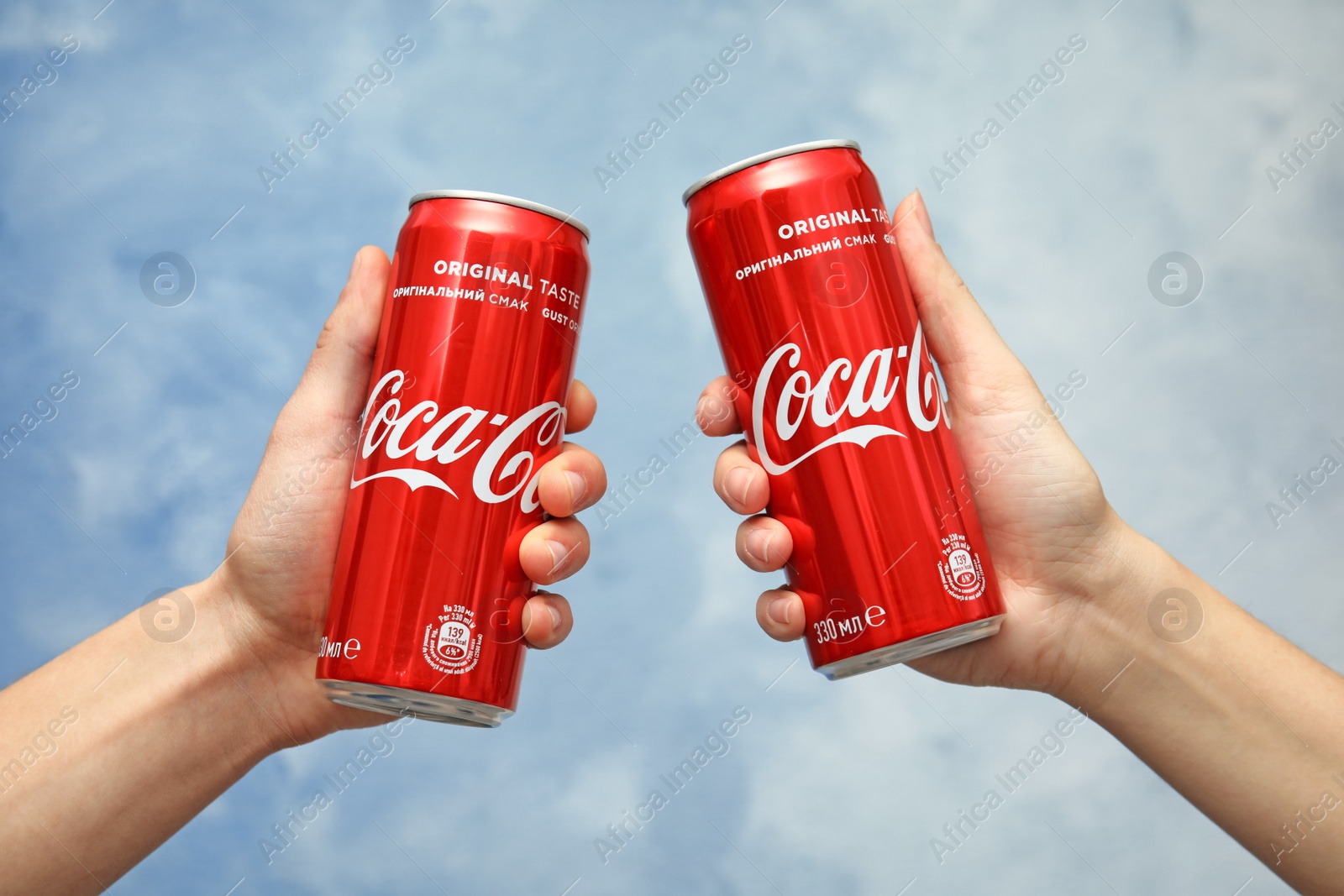 Photo of MYKOLAIV, UKRAINE - NOVEMBER 15, 2018: People with Coca Cola cans on color background, closeup