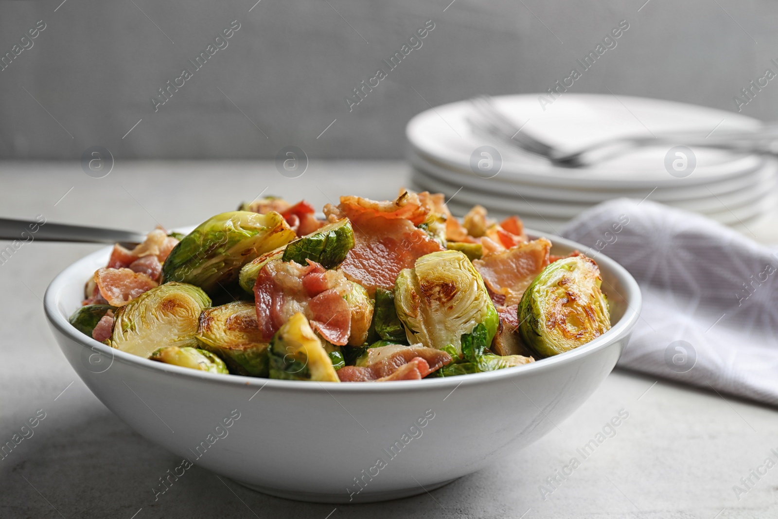 Photo of Delicious roasted Brussels sprouts with bacon served on light grey table