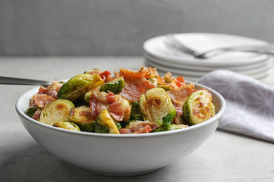 Photo of Delicious roasted Brussels sprouts with bacon served on light grey table