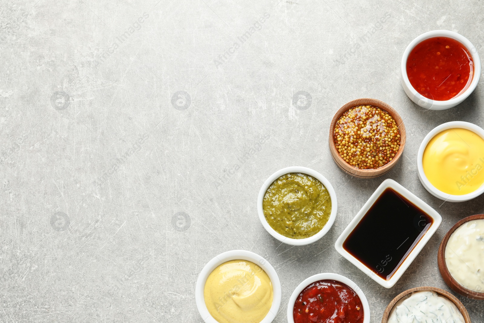 Photo of Set of different delicious sauces on grey table, top view. Space for text