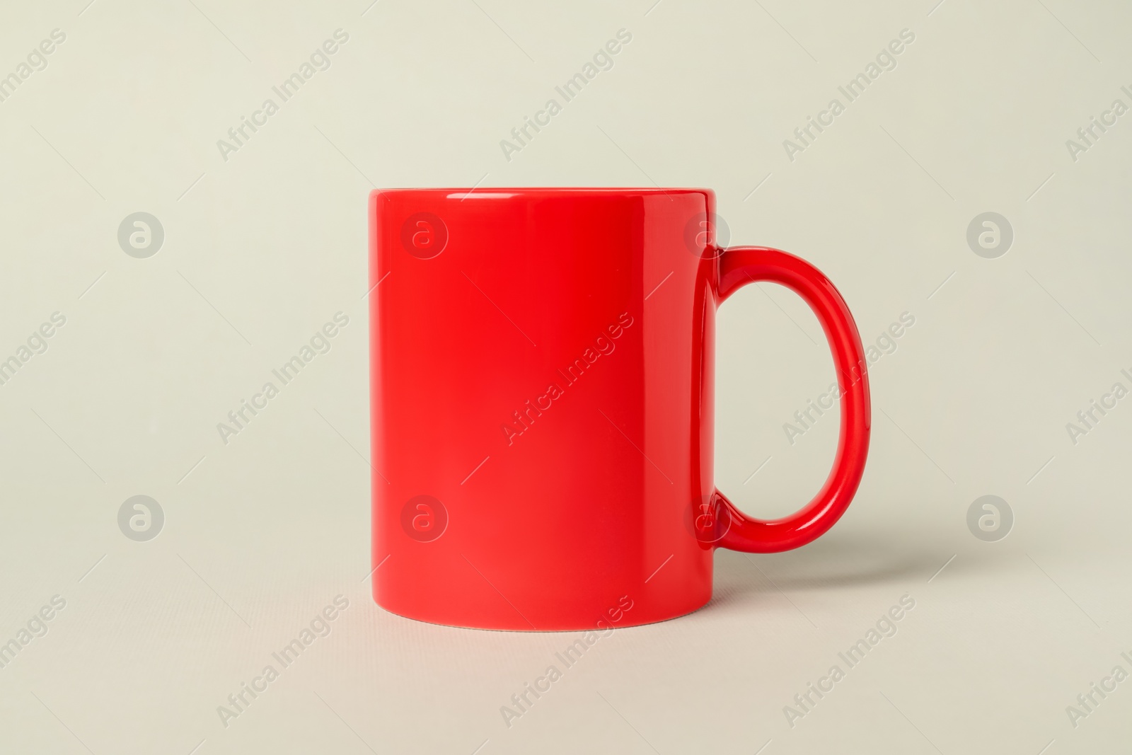 Photo of One red ceramic mug on light grey background