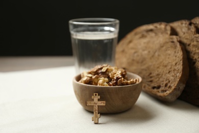 Photo of Bread, walnuts, water and crucifix on table. Great Lent season
