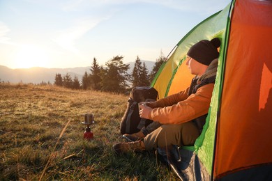 Photo of Man with cup of hot drink in camping tent. Space for text