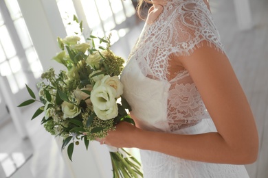 Photo of Bride in beautiful wedding dress with bouquet indoors, closeup