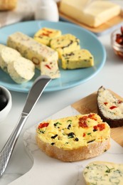 Photo of Different types of tasty butter, bread and knife on white table