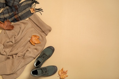 Photo of Flat lay composition with sweater and dry leaves on beige background, space for text. Autumn season