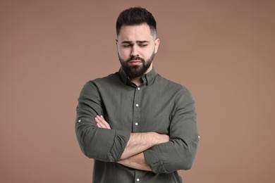 Photo of Portrait of sad man with crossed arms on brown background