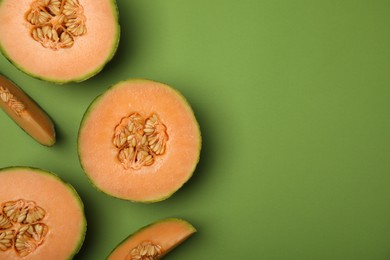Photo of Cut melons on green background, flat lay. Space for text