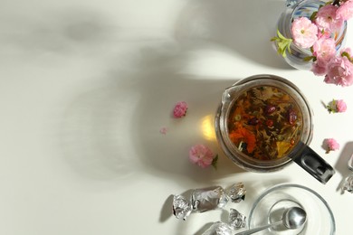 Photo of Flat lay composition with freshly brewed tea and beautiful flowers on light table. Space for text