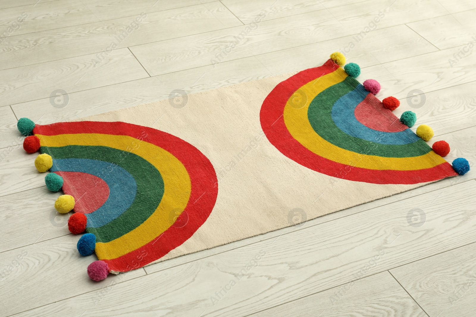 Photo of Stylish rug with rainbow on white wooden floor