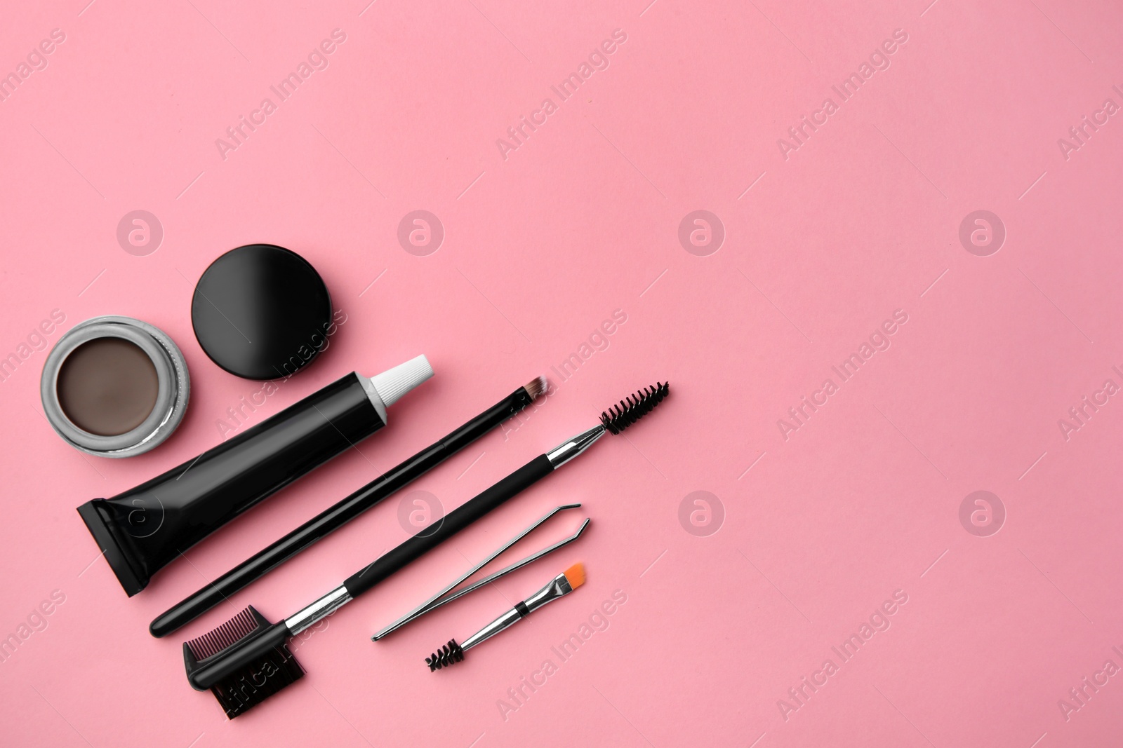 Photo of Flat lay composition with eyebrow henna and tools on pink background. Space for text