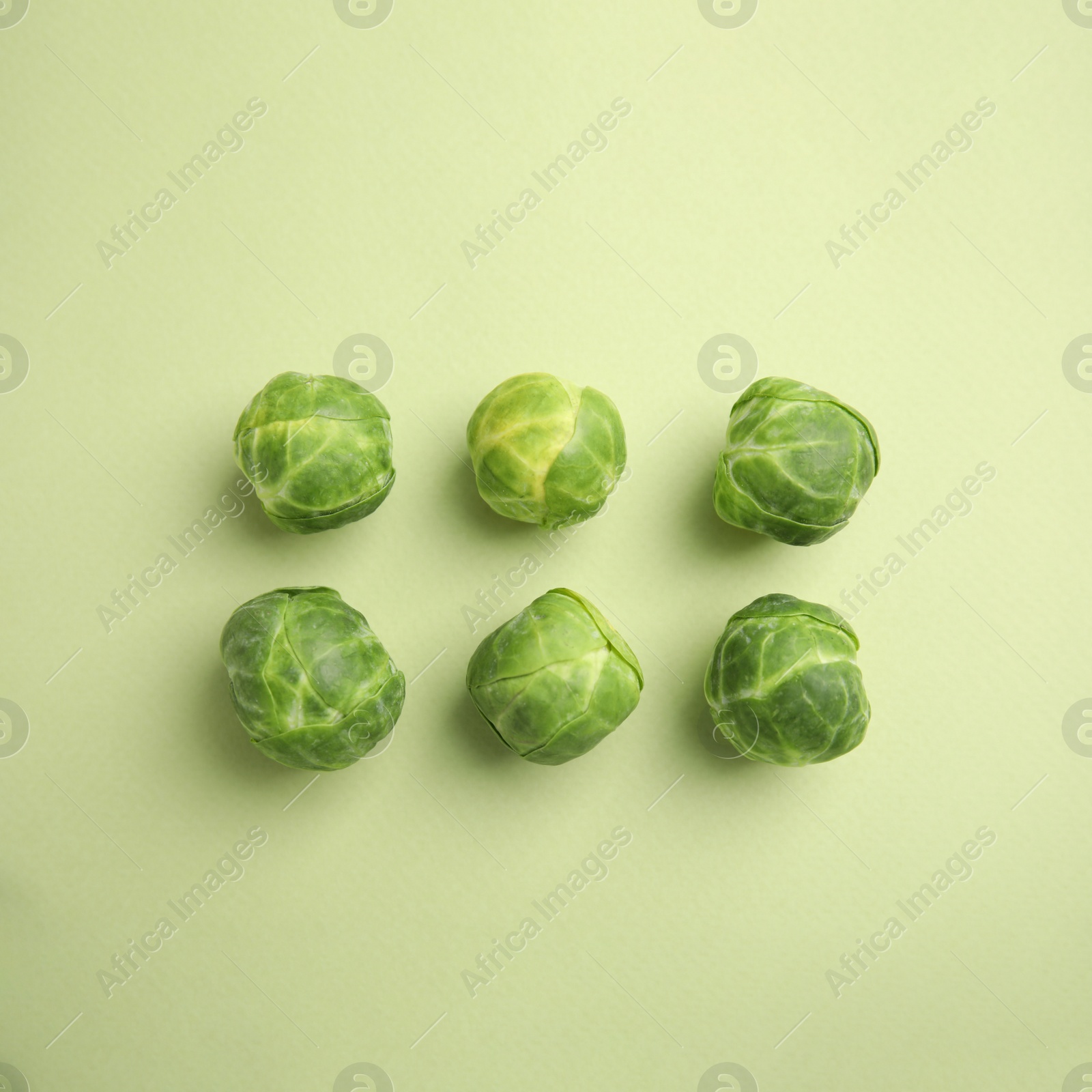 Photo of Fresh Brussels sprouts on green background, flat lay