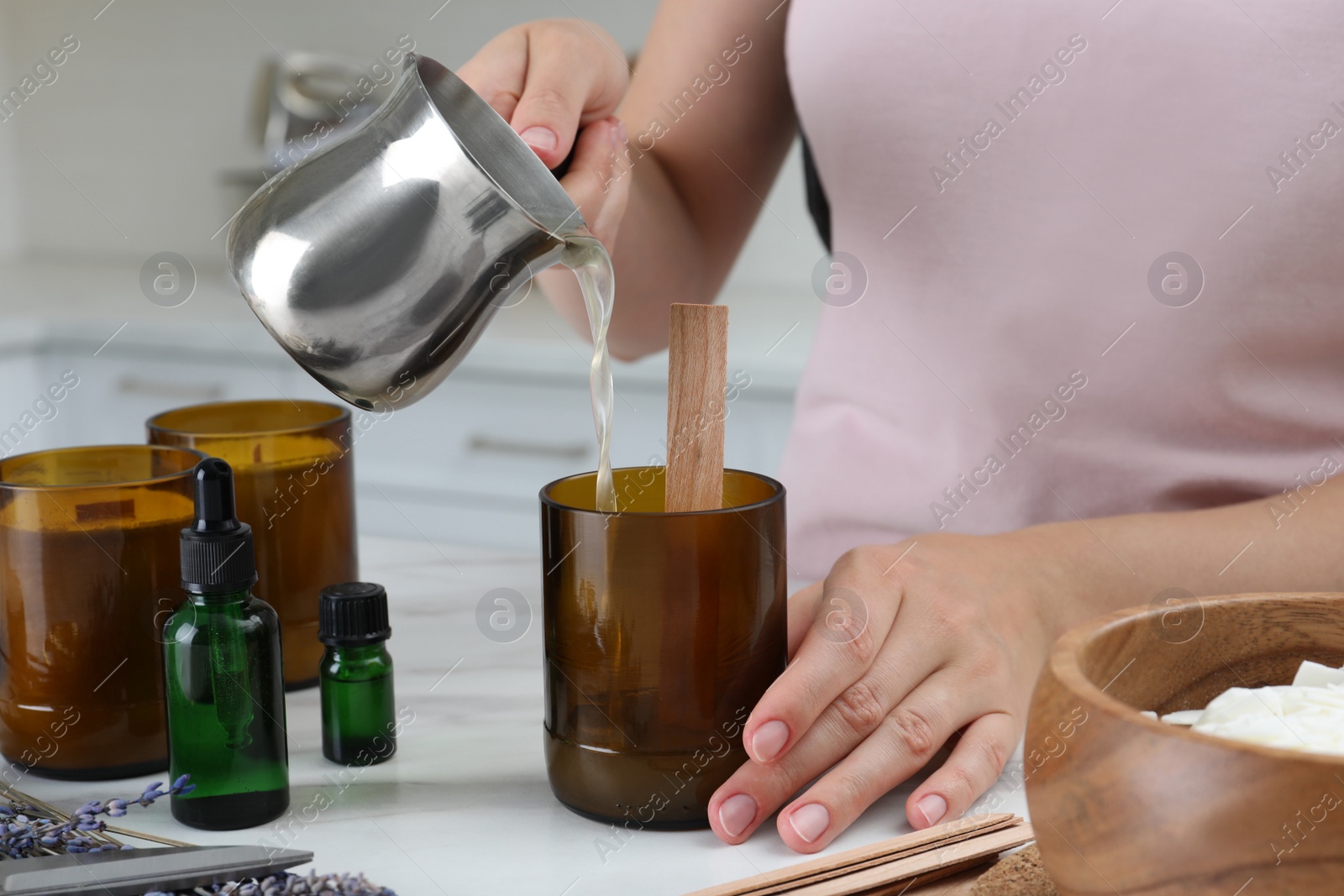 Photo of Woman making homemade candle at table in kitchen, closeup