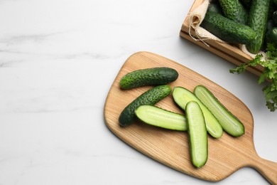 Photo of Fresh ripe cucumbers and parsley on white marble table, flat lay. Space for text