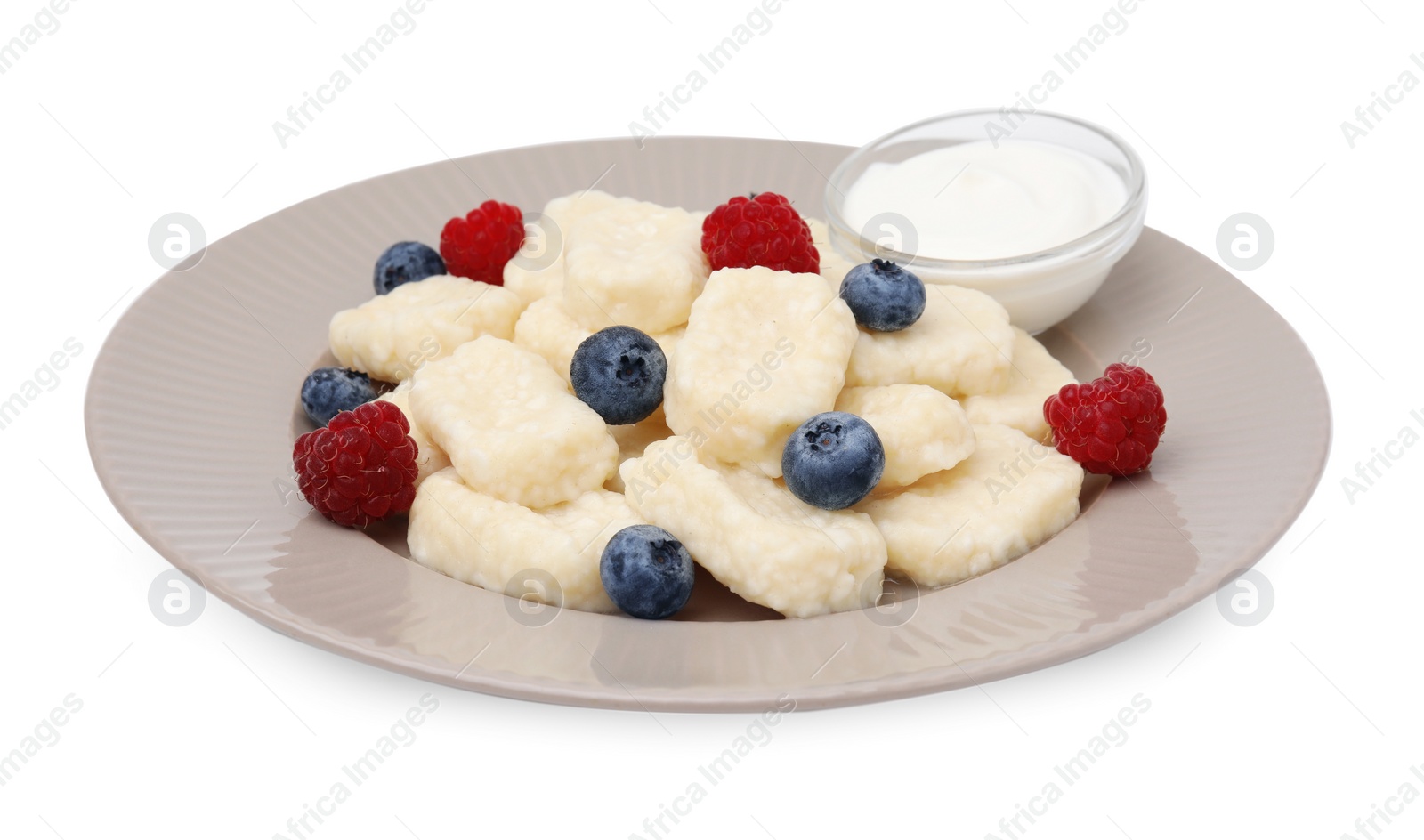 Photo of Plate of tasty lazy dumplings with berries and sour cream isolated on white