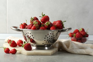 Photo of Metal colander with fresh strawberries on grey countertop