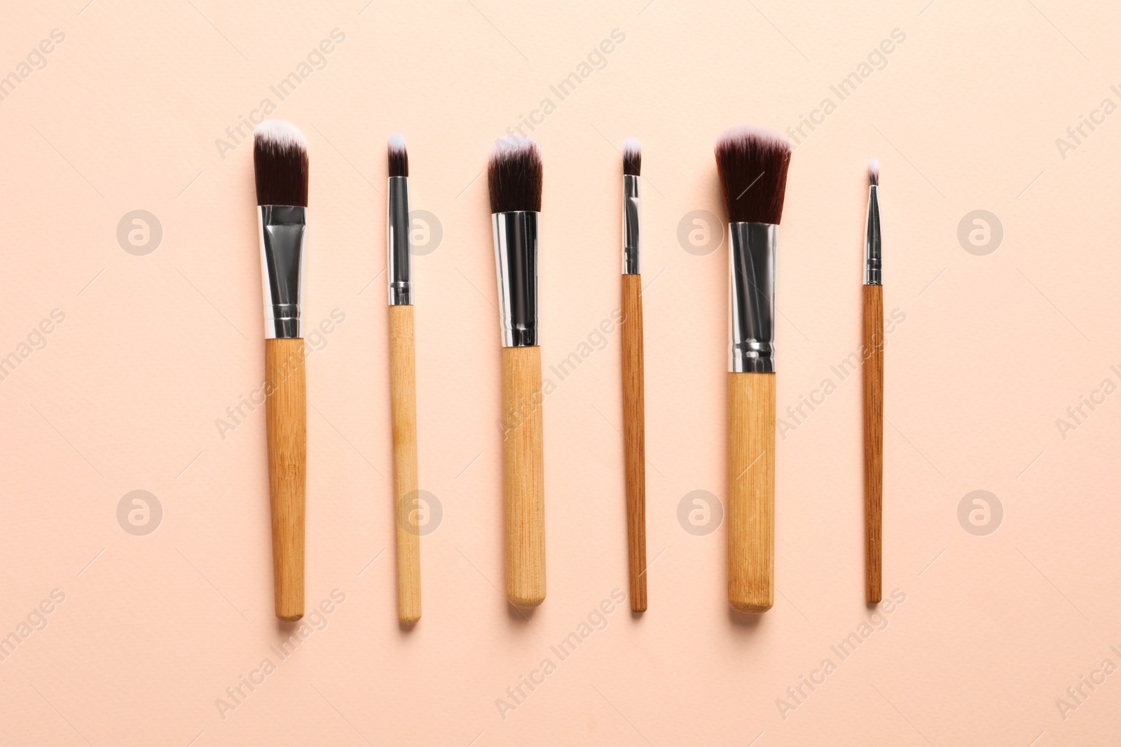 Photo of Set of makeup brushes on beige background, flat lay