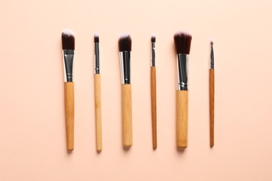 Photo of Set of makeup brushes on beige background, flat lay
