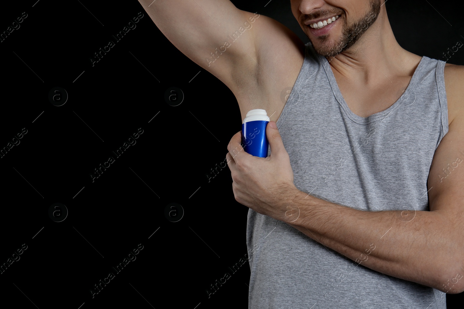 Photo of Man applying deodorant on black background, closeup. Space for text