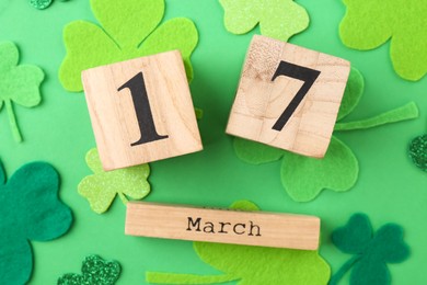 Photo of St. Patrick's day - 17th of March. Block calendar and decorative clover leaves on green background, flat lay