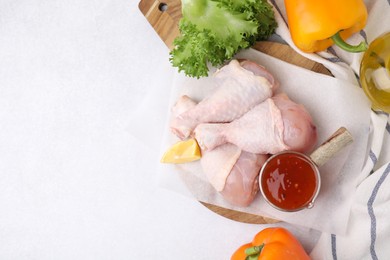Photo of Flat lay composition with marinade and raw chicken drumsticks on white table. Space for text