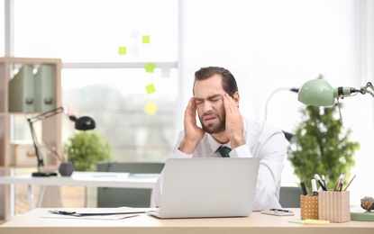 Young man suffering from headache in office