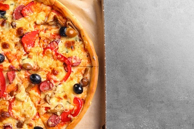 Cardboard box with delicious pizza on table, top view