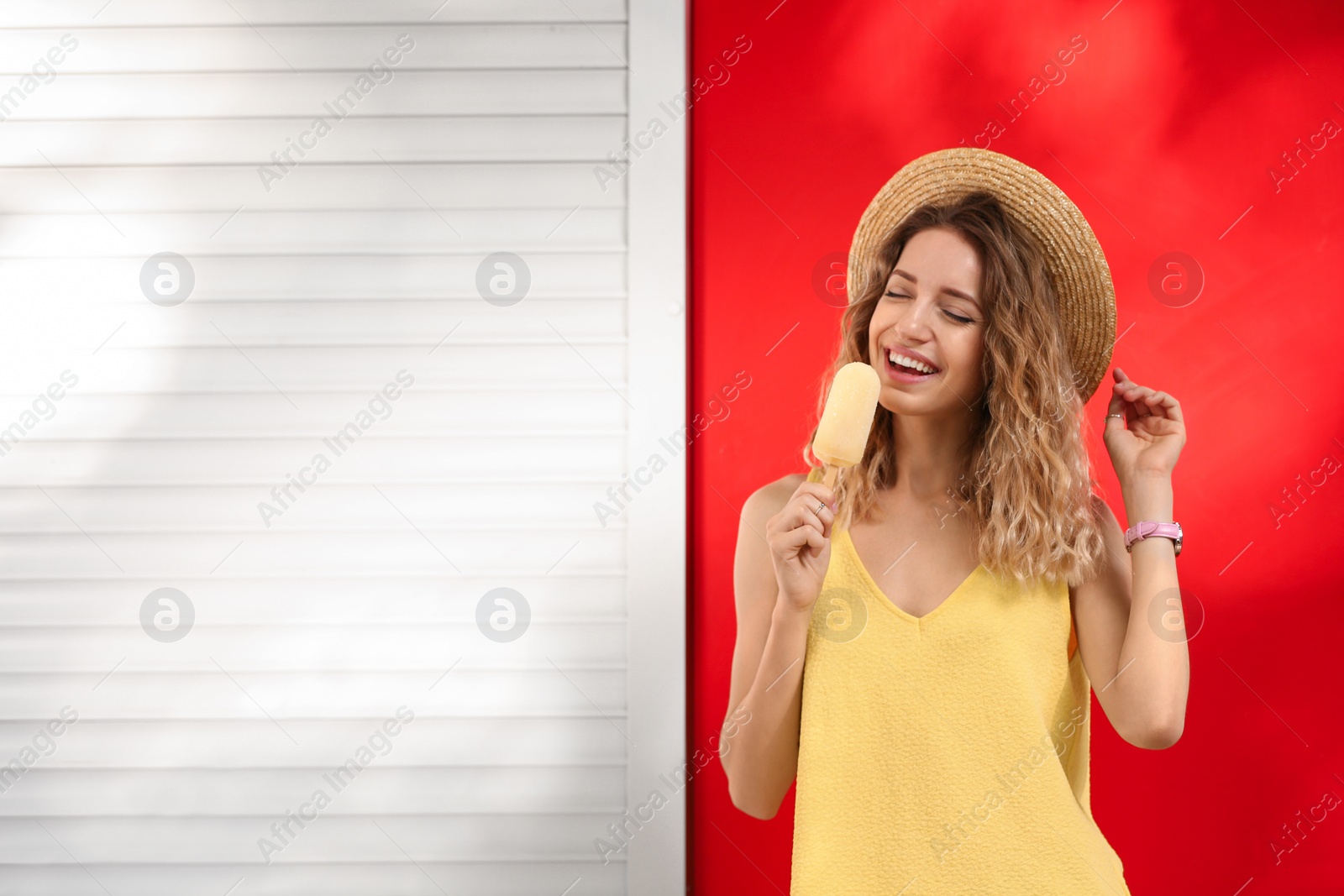 Photo of Happy young woman eating delicious ice cream near color wall. Space for text
