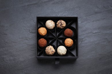 Photo of Box of tasty chocolate candies on black table, top view