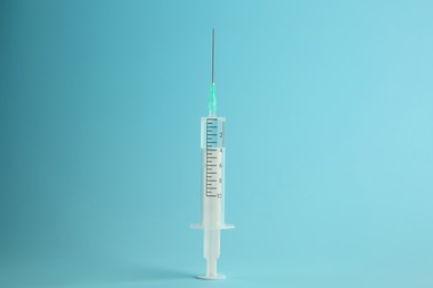 Photo of Medical syringe with liquid on light blue background