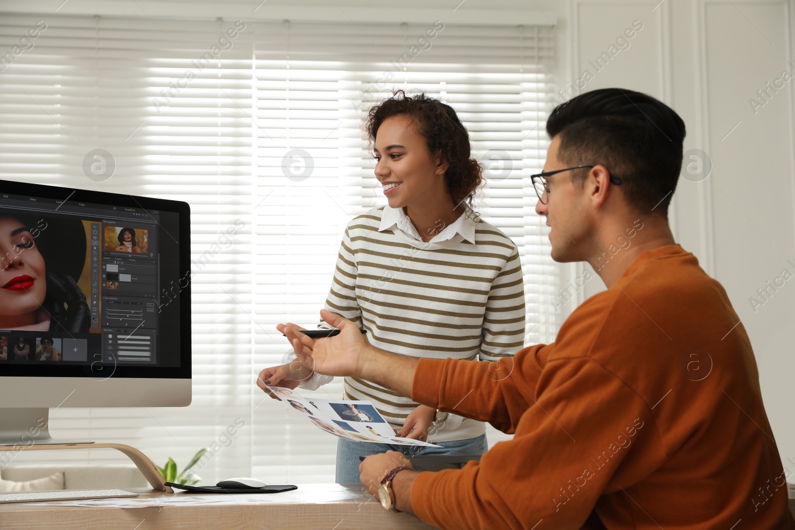 Photo of Professional retoucher with colleague working at desk in office