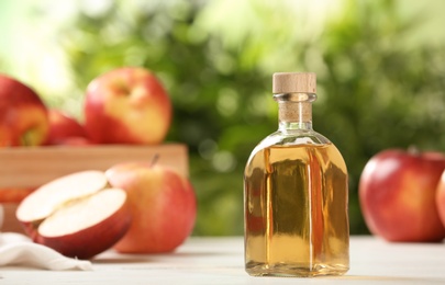 Photo of Composition with bottle of apple vinegar on table. Space for text