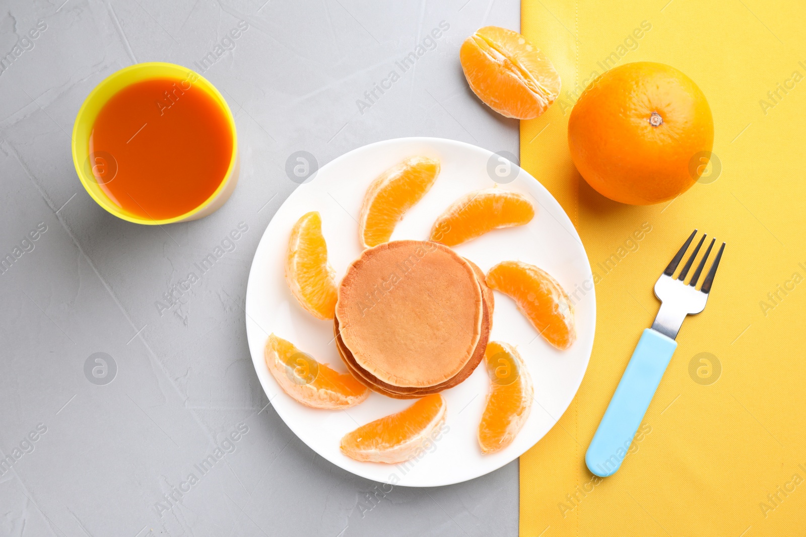 Photo of Tasty pancakes served with orange and juice on grey table, flat lay. Creative idea for kids breakfast