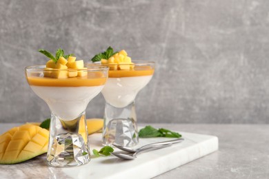 Photo of Delicious panna cotta with mango coulis served on light grey table. Space for text