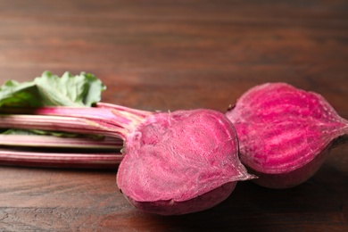 Photo of Halves of raw beet on wooden table, closeup