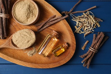 Dried sticks of licorice root, powder and essential oil on blue wooden table, flat lay