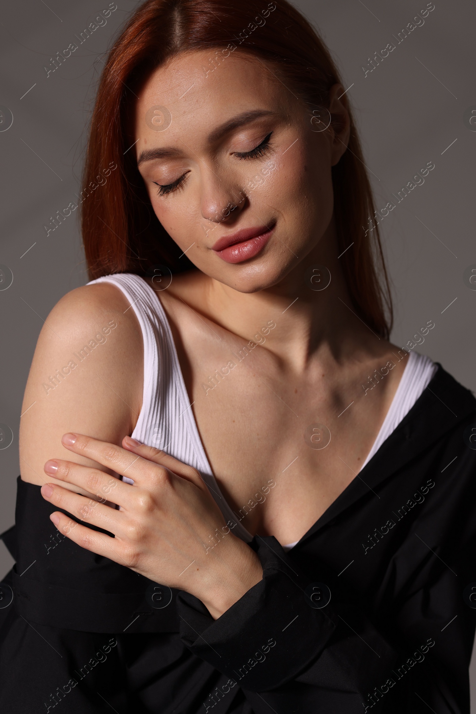 Photo of Beautiful young woman in black shirt on gray background