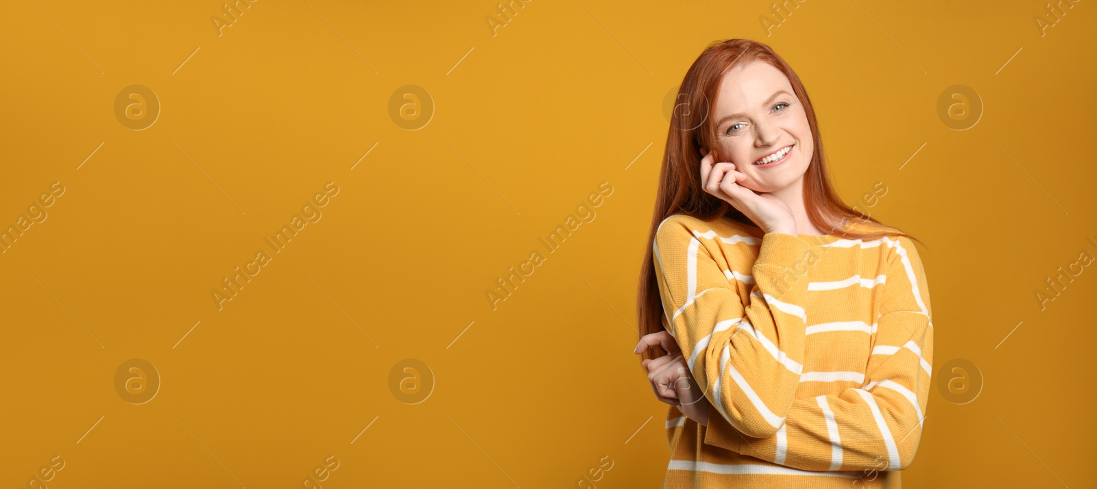 Photo of Candid portrait of happy young woman with charming smile and gorgeous red hair on yellow background