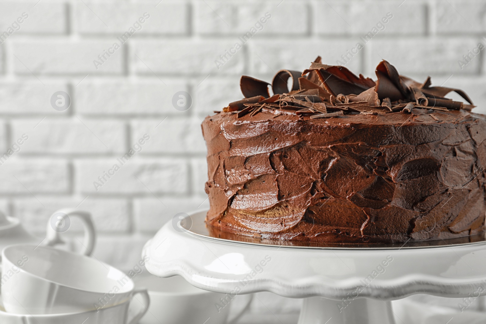 Photo of Stand with tasty homemade chocolate cake near white brick wall