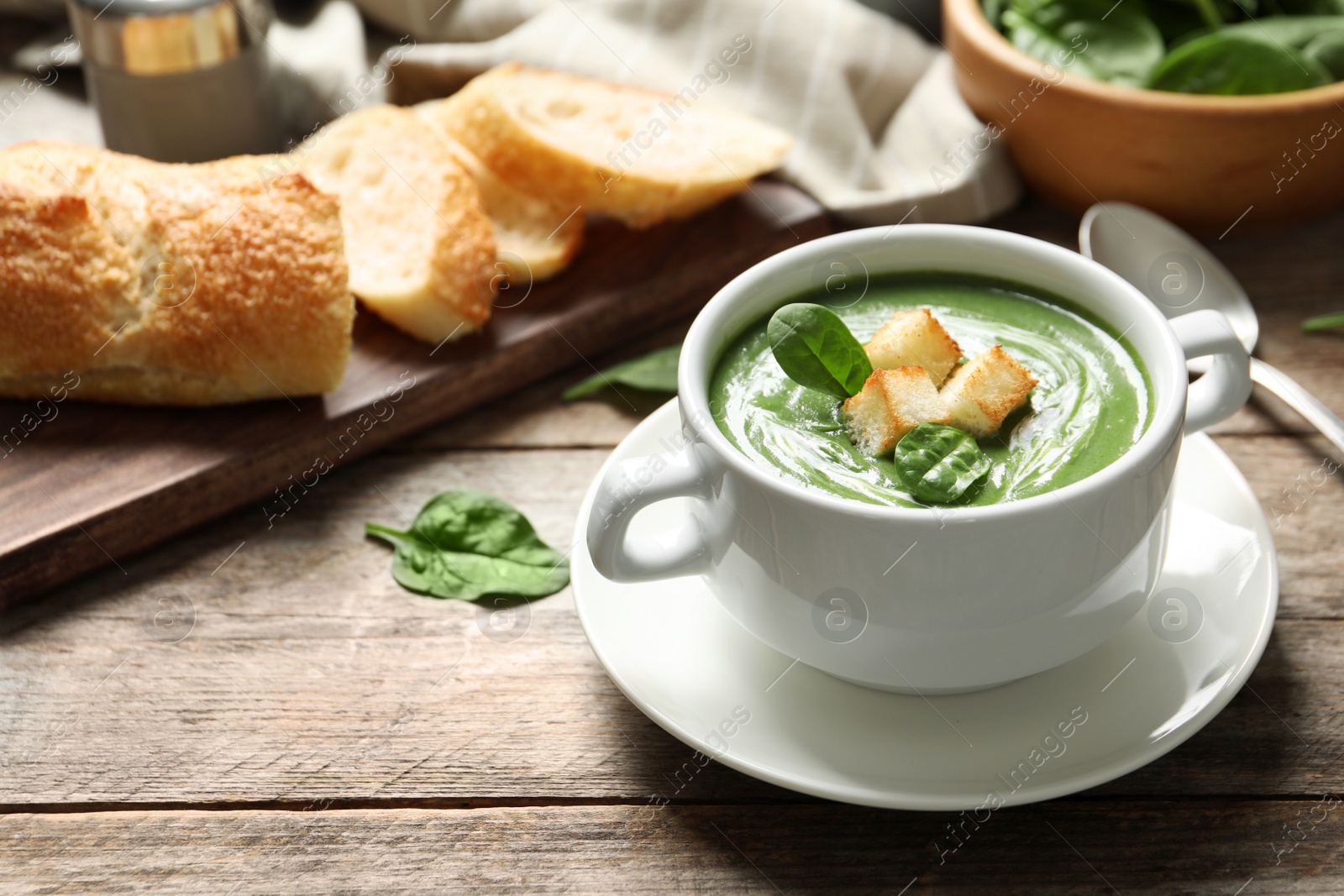 Photo of Fresh vegetable detox soup made of spinach with croutons in dish served on table. Space for text